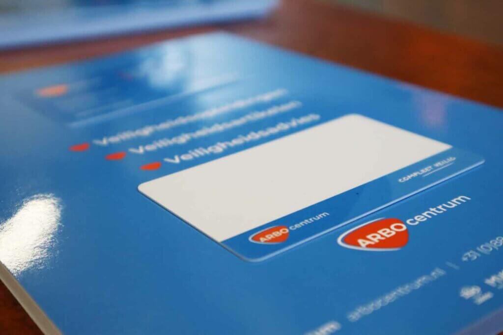 Een close-up van een blauwe veiligheidsinstructiekaart, met het logo van ARBO centrum met een rood hart-icoon en tekstvelden voor het invullen van essentiële gegevens. De kaart hint subtiel naar 3 redenen waarom een EPT certificaat nodig is, tegen een zacht wazige achtergrond.